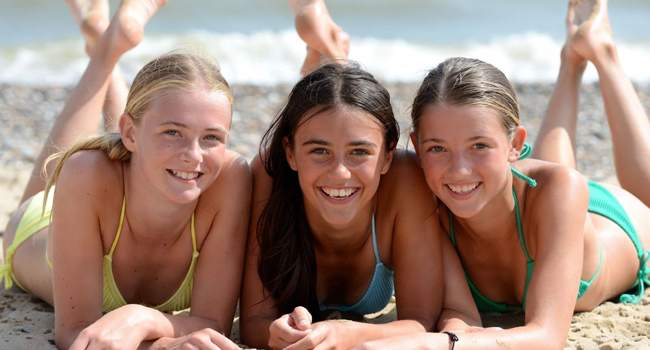 Schoolgirls on the beach in Exmouth during a LISA! language study holiday lying in the sand enjoying the sun and sea