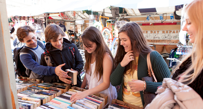 Adults shopping at a market in Cambridge City England during a LISA! language study holiday browsing books and enjoying free time