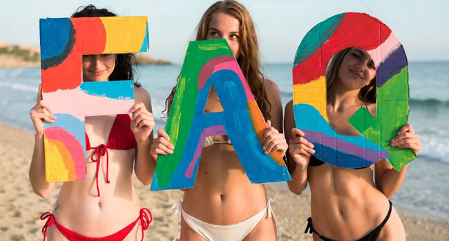 FAQs about LISA! language study holidays in Malta – students holding colourful letters on the beach Three female students on the beach holding colourful FAQ letters during a LISA! language study holiday in Malta