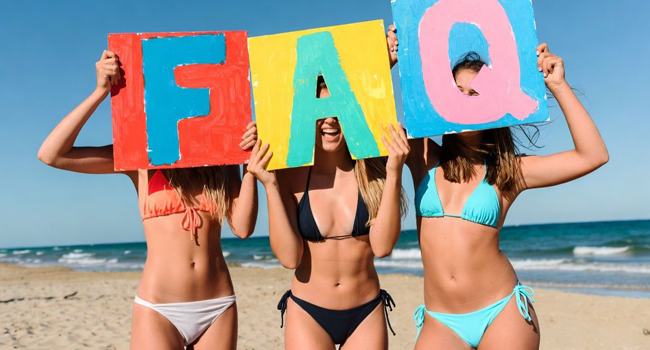 Language study holidays in Malta for adults: FAQs and answers Adult female participants on a language study holiday in Malta on the beach with signs for frequently asked questions and answers