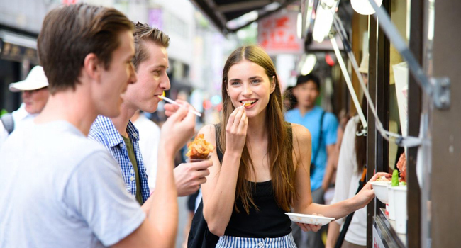 Educational leave Osaka Japan with LISA! – learning Japanese, street food and authentic experiences Adults trying street food in Osaka during a LISA! educational leave language study holiday experiencing Japanese food culture and international city life