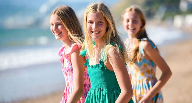 Language study holidays in England Bournemouth with LISA! – beach, summer and unforgettable experiences Three schoolgirls on the beach in Bournemouth England during a LISA! language study holiday wearing summer dresses and enjoying the sea