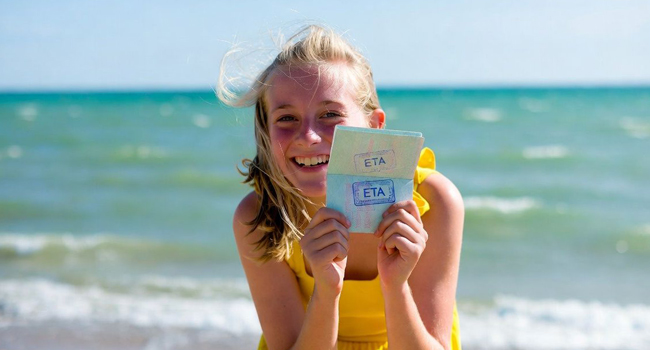 Schoolgirl on the beach in Exmouth during a LISA! language study holiday showing ETA entry document for England