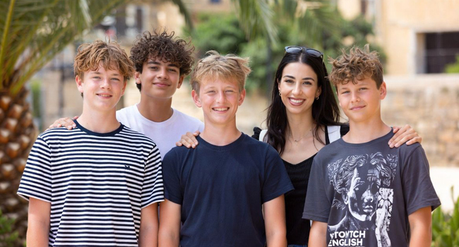 Supervision during a language study holiday for students in Malta San Gwann Supervisor and teacher with four boys in front of a palm tree on a language study holiday in Malta San Gwann