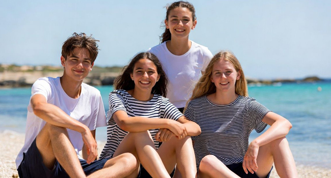 Student language study holidays in Malta with LISA! – group of students on the beach Four students sitting on the beach in Malta during a LISA! language study holiday for students