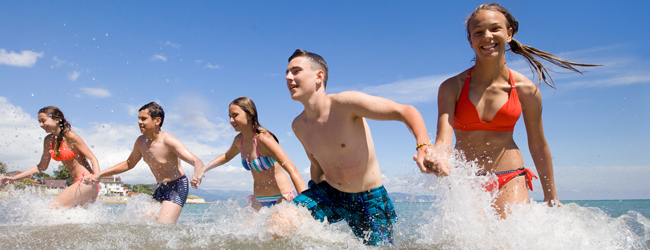 A group of young people laughing as they run through the sea during a LISA! language trip in Sliema