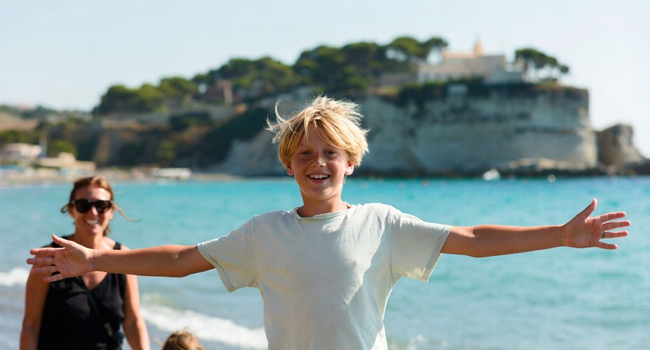 Language study holidays in Italy Tropea for students with LISA! – arrival, beach and first impressions Young student on the beach in Tropea Italy celebrating arrival during a LISA! language study holiday