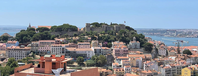 Hügel von Lissabon mit Meerblick bei einer LISA! Sprachreise Portugiesisch Hügel mit Gebäuden und Blick auf das Meer bei einer Sprachreise in Lissabon
