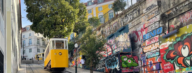 Mit der Strassenbahn durch Lissabon bei einer LISA! Sprachreise Strasse in Lissabon mit gelber Strassenbahn, die einen Hügel hinauffährt