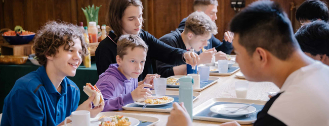 Schüler sitzen an einem Tisch und essen zu Mittag in der Cafeteria der Schule in Ardingly