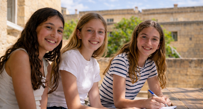 Eine LISA! Schülersprachreise Malta Sliema im Sommer Drei Mädchen sitzen draussen in Malta Sliema und lernen gemeinsam und lachen in die Kamera